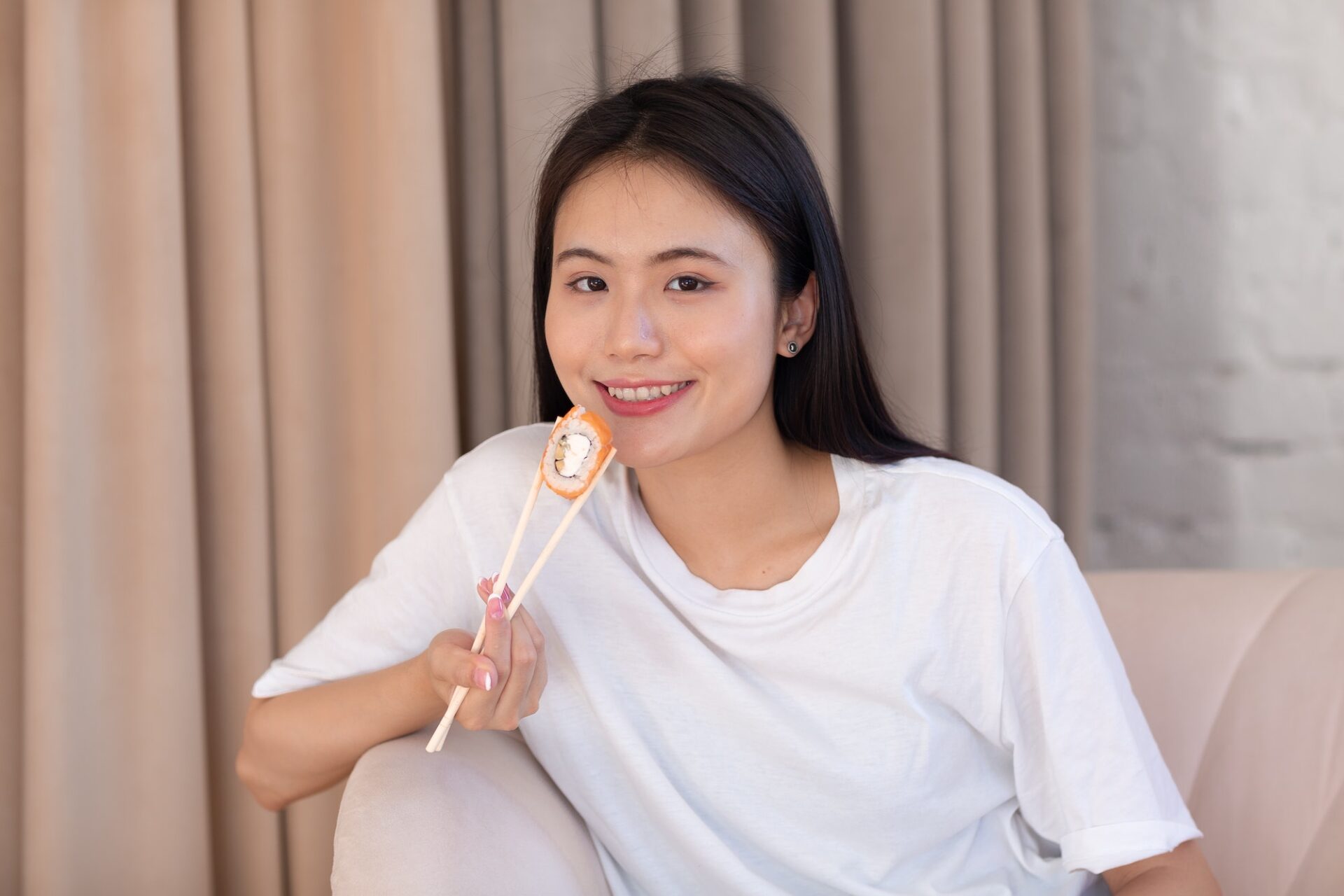 Asian beauty model girl eating Sushi roll, healthy japanese food. Beautiful woman holding chopsticks